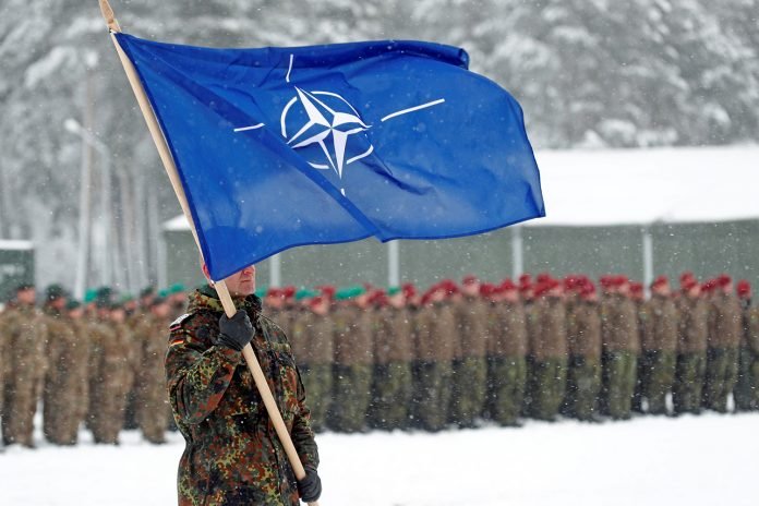 A soldier carries the NATO flag during German Minister of Defence Ursula von der Leyen's visit to German troops deployed as part of NATO enhanced Forward Presence (eFP) battle group in Rukla military base